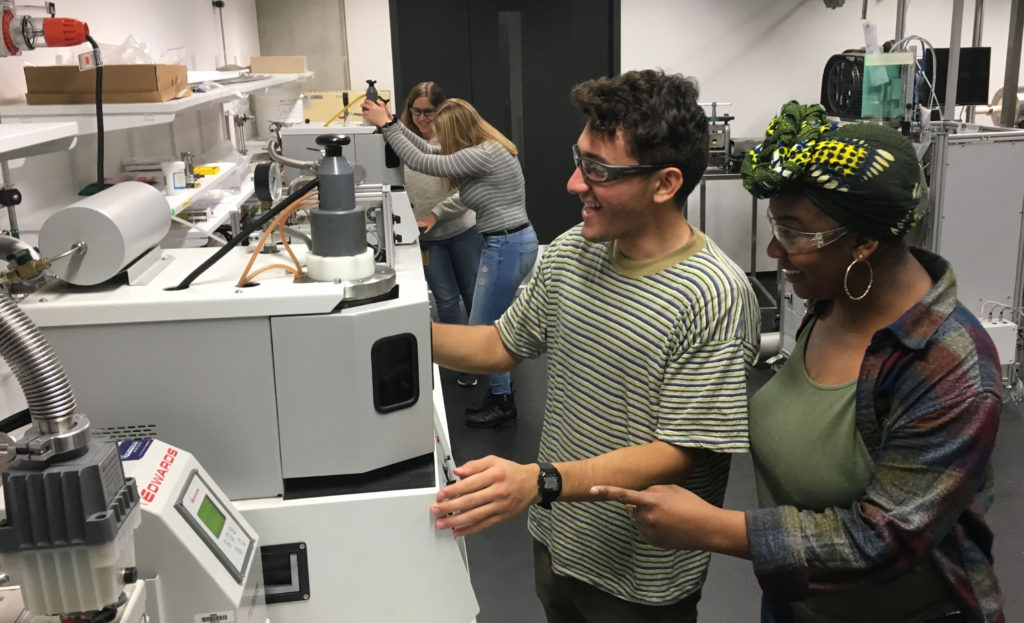 People working on big gray machine in a lab.