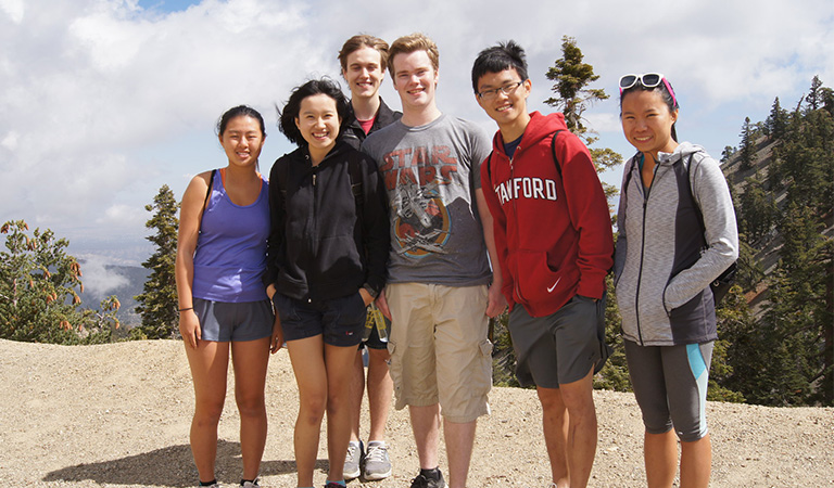 Students posing for a photo on top of a mountain.