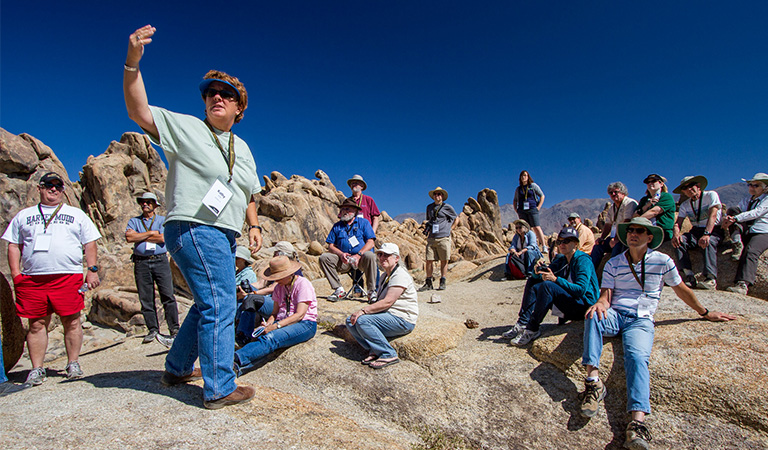 Students and faculty sitting and discussing on top of a mountain.