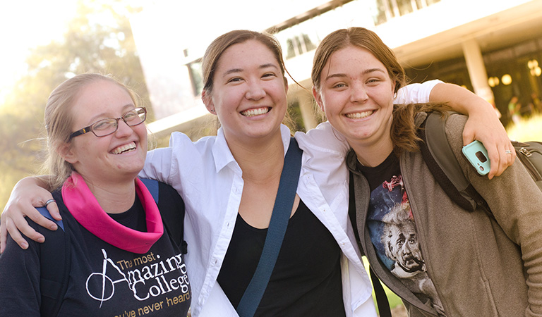 Three friends hugging and smiling.