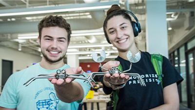 Students holding up welded metal crabs.
